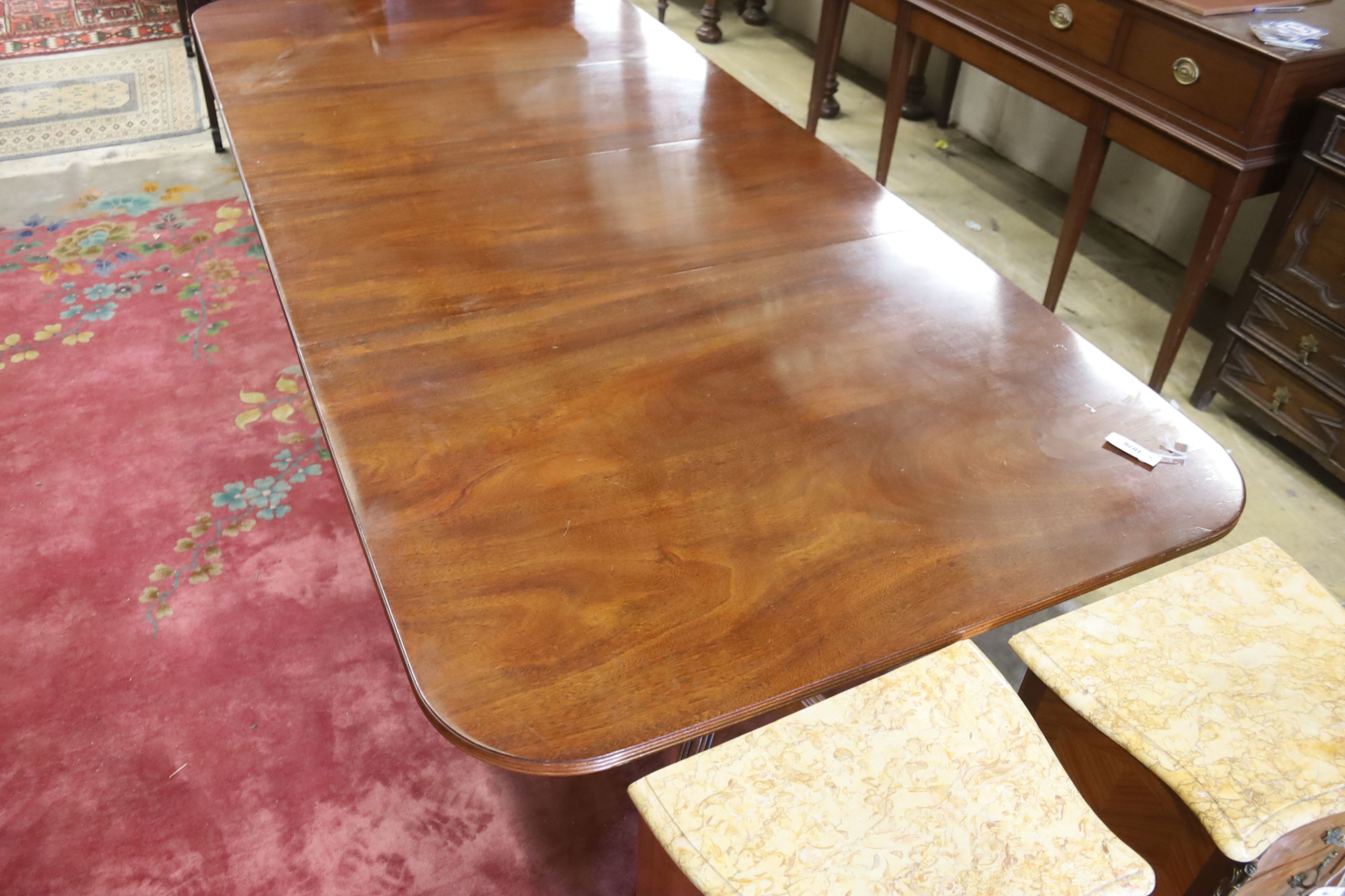 A reproduction George III style mahogany twin pillar extending dining table, two spare leaves, length 244cm extended, width 107cm, height 72cm
